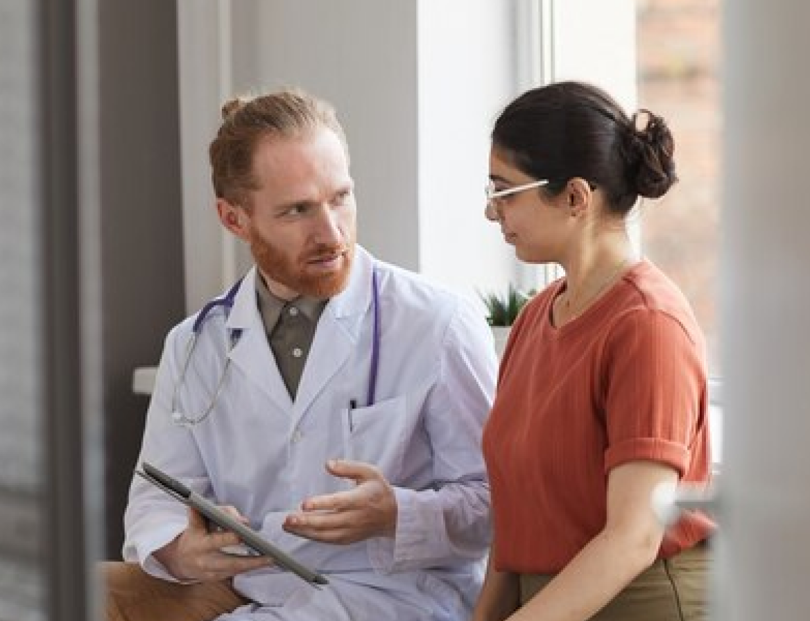 Doctor consulting with a patient using digital tools to optimize scheduling and reduce wait times.