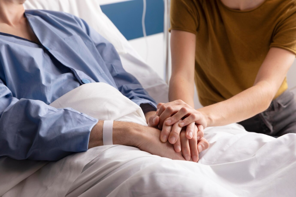 About Us 5 Supportive hand-holding at a hospital bedside symbolizing compassionate patient care.