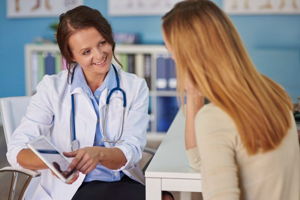 Pharmacovigilance & Safety Monitoring 1 Pharmacovigilance expert discussing AI literature search results with a healthcare professional in an office setting.