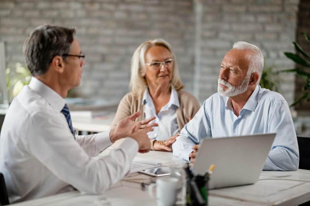 Underwriting Support & Decision Intelligence for Healthcare Payers 1 Senior couple discussing health insurance policy with a healthcare underwriting advisor.