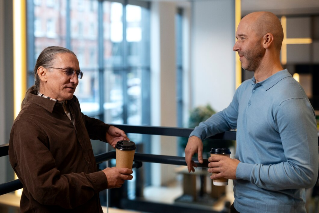 About Us 12 Two professionals having a casual coffee chat in a modern office setting.